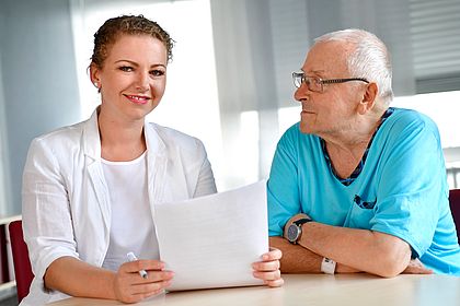 Bild mit Verlinkung: Ein Patient im Gespräch mit einer Sozialberaterin. Hier gelangen Sie zum